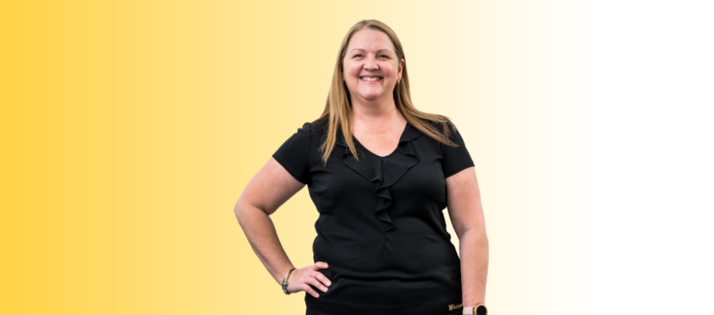 Leanne is smiling at camera wearing a black uniform with a yellow gradient background